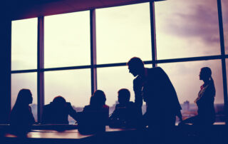 Several colleagues meeting in office silhouetted against a window background