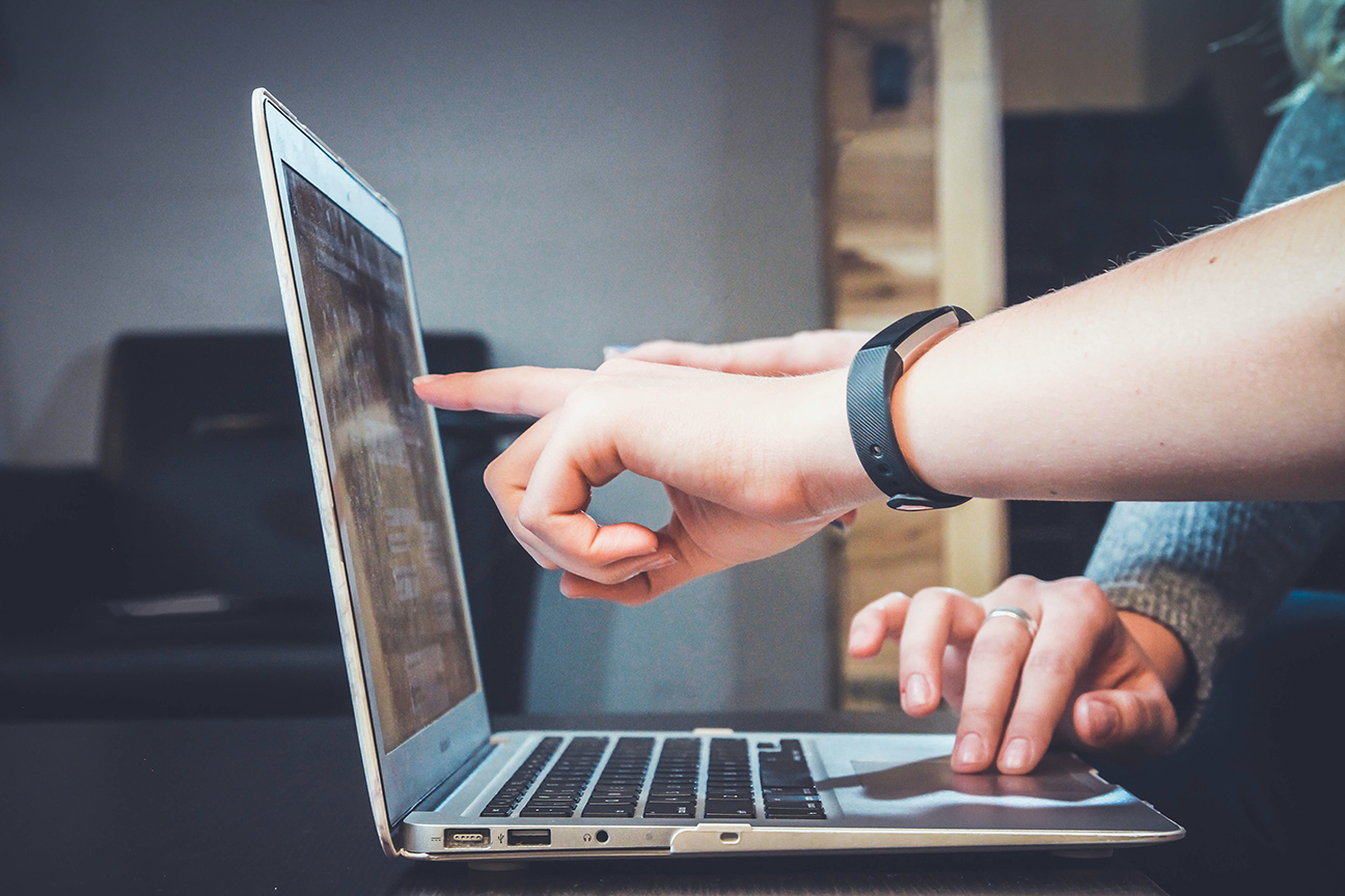 close up of two people pointing at the screen of a laptop