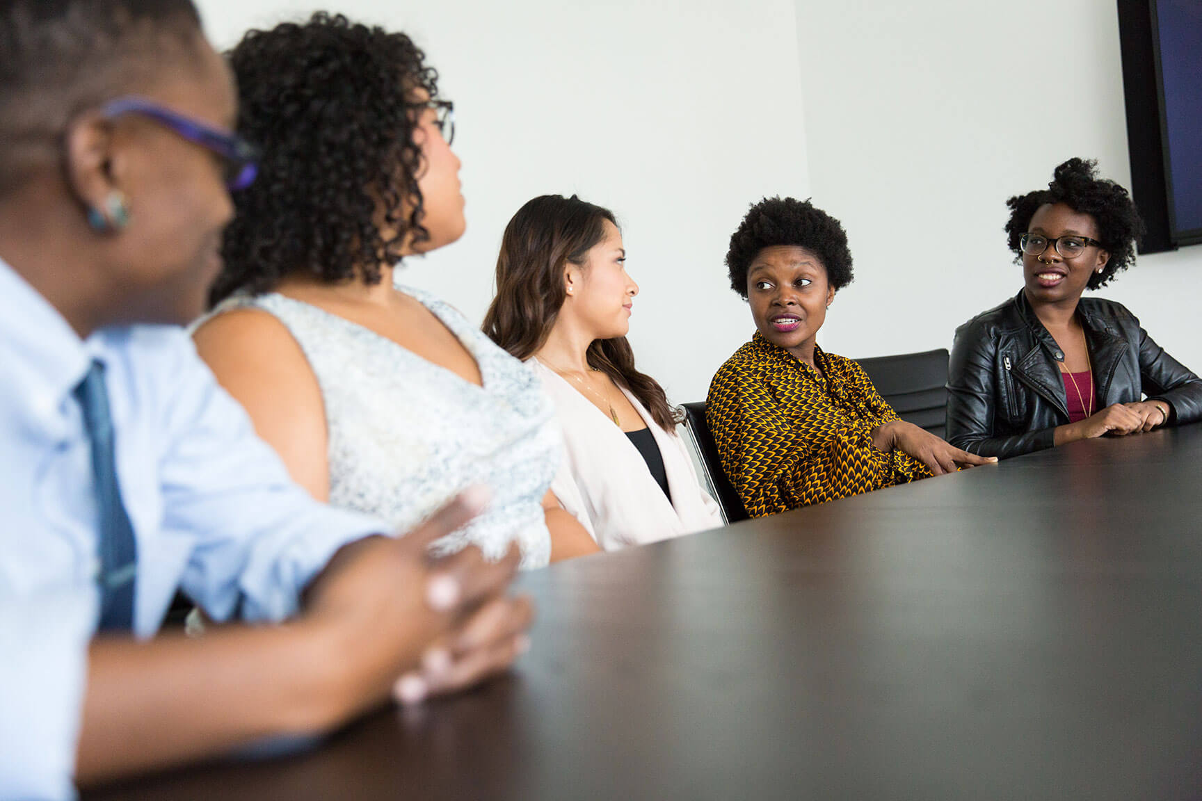 group of adults gathered at a table conversing with each other