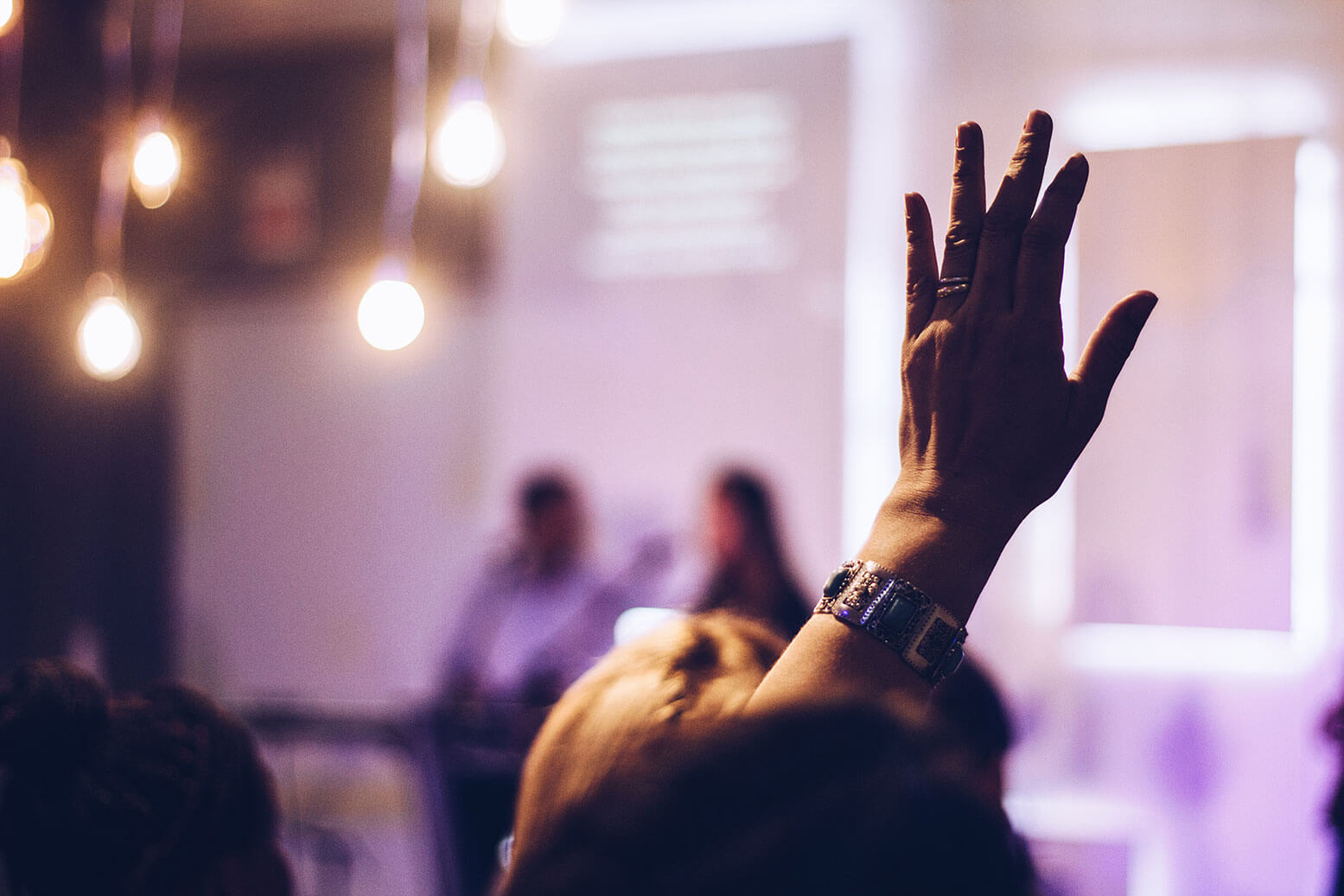 individual raises hand in a meeting