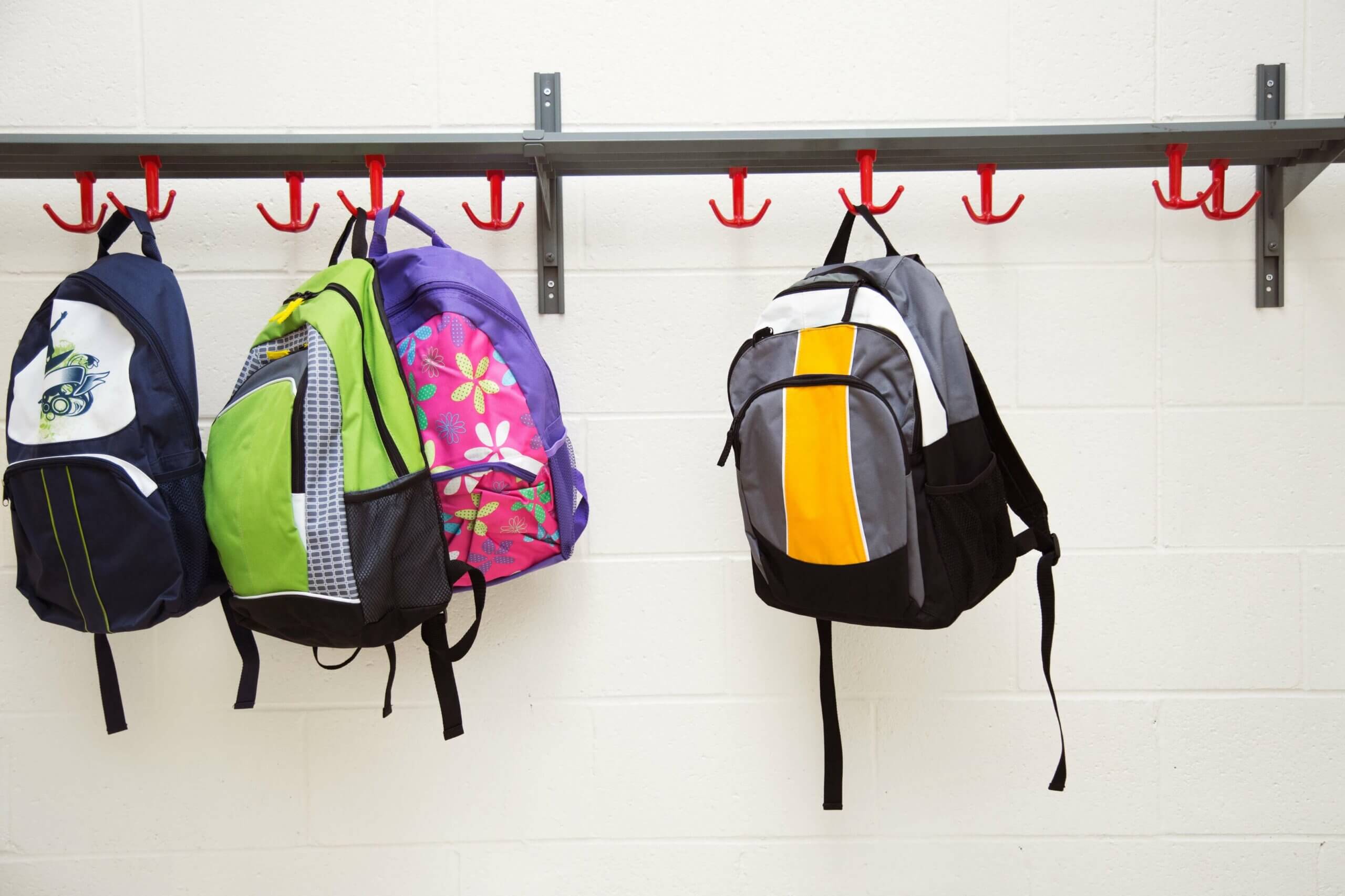 multiple backpacks stored on a hanging rack