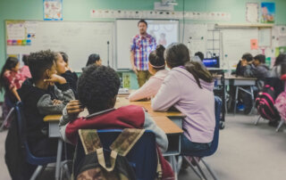 Group of students in classroom looking at teacher